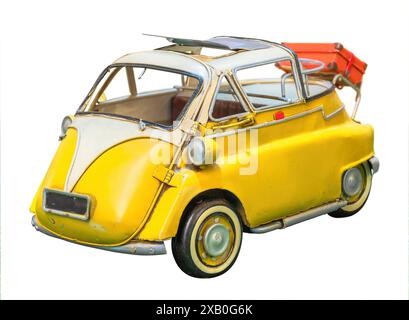 Riproduzione isolata di un giocattolo indipendente giallo d'epoca di una microcar retrò agganciata su uno sfondo bianco e dotata di tettuccio apribile con un bagaglio sul retro Foto Stock