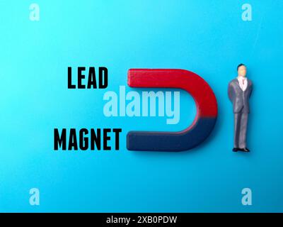 Persone e magnete in miniatura con MAGNETE IN PIOMBO su sfondo blu. Concetto di business. Foto Stock