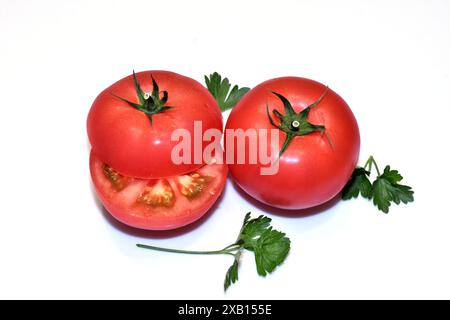 Due pomodori rossi maturi, uno tagliato a metà. Foto Stock