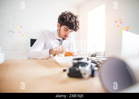 Uomo d'affari che sta pranzando veloce, pasto veloce nell'ufficio della startup. Foto Stock