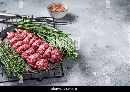 Kebab di Urfa Turco crudo decorato con erbe, spezie e forchetta di carne. Sfondo grigio. Vista dall'alto. Spazio di copia. Foto Stock