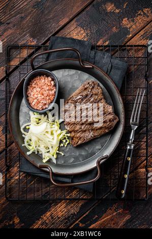 Bistecca di cervo con sale marino e insalata. Sfondo di legno. Vista dall'alto. Foto Stock