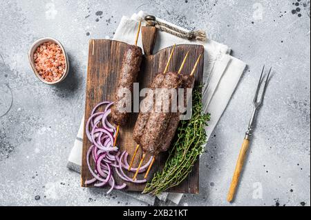 Kofta alla griglia kofte shish kebab di agnello trito e carne di manzo su spiedino. Sfondo grigio. Vista dall'alto. Foto Stock