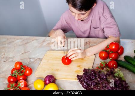 ragazzo che taglia un pomodoro in cucina Foto Stock