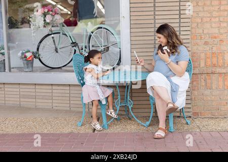 mamma scatta foto a una figlia fuori da una piccola boutique Foto Stock