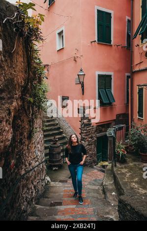 Donna che salta i gradini di una strada stretta e colorata a Vernazza, Italia. Foto Stock