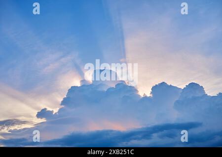 Vista ad angolo basso della luce del sole che scorre attraverso le nuvole al tramonto Foto Stock