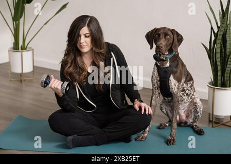 Donne sedute su un tappetino da yoga accanto a un puntatore a pelo corto tedesco Foto Stock