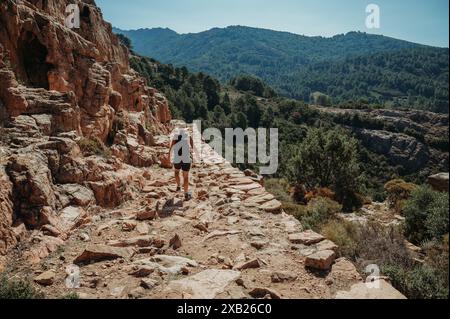 Donna che fa un'escursione nelle aspre montagne della Corsica che si affacciano sulla valle Foto Stock