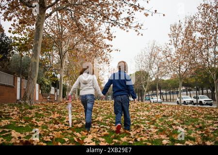 due bambini che camminano e parlano insieme amichevolmente all'aperto. Famiglia. Vista posteriore Foto Stock