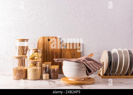 Un bellissimo sfondo della cucina con un vano portaoggetti per i prodotti sfusi in vasetti di vetro, piatti nell'asciugatrice, una grande ciotola su un ripiano in marmo Foto Stock