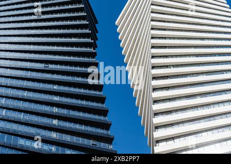 Questa immagine mostra i moderni grattacieli a spirale sotto un cielo blu limpido a Tbilisi, illustrando la dinamica crescita architettonica della popolazione georgiana Foto Stock