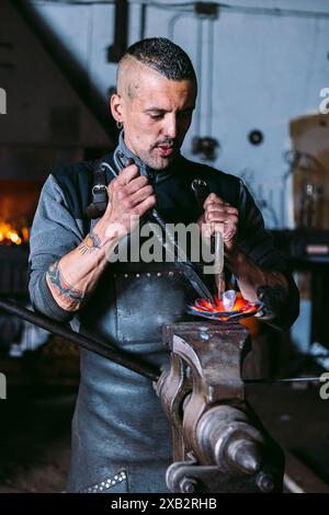 Fabbro maschio che forgia metallo con martello in officina tradizionale Foto Stock