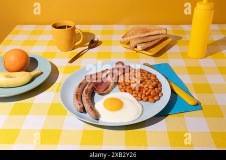 In una tovaglia colorata si stende un piatto blu contenente una deliziosa colazione con uova, fagioli e salsicce, e ci sono alcune fette di pane, una tazza di c Foto Stock