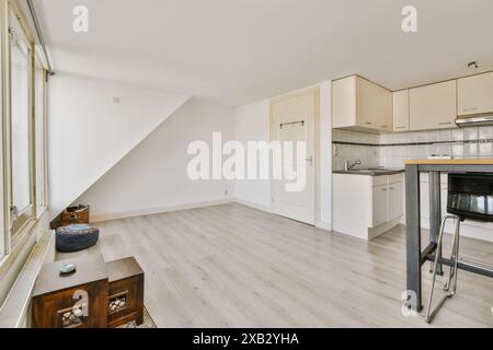 Interni luminosi e ariosi con pareti bianche, cucina moderna e mobili in legno minimalista sotto luce naturale. Foto Stock