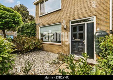 Un'accogliente casa suburbana situata sulla Roggebotstraat ad Amsterdam presenta un giardino frontale ben curato, una facciata in mattoni e grandi finestre, che mescolano modernità Foto Stock