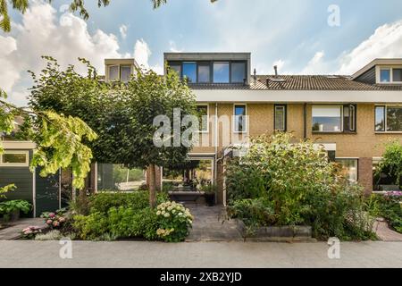 Elegante residenza a Rosendael, Amsterdam, caratterizzata da un giardino frontale lussureggiante e ben tenuto con un vivace fogliame e un'accogliente area salotto all'ombra Foto Stock