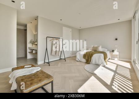 Una spaziosa camera da letto moderna con luce naturale, pavimento in parquet a spina di pesce, tavolozza di colori delicati e mobili minimalisti che creano un ambiente sereno Foto Stock