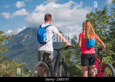 Due turisti ciclisti su mountain bike elettriche che si godono uno splendido paesaggio montuoso Foto Stock