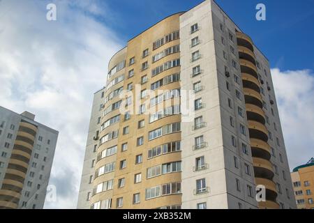 Un grattacielo si erge alto sullo sfondo di un cielo azzurro limpido, mostrando un moderno design urbano e un paesaggio urbano con la sua facciata elegante e i numerosi windo Foto Stock