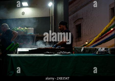 Il venditore griglierà il cibo in un chiosco di strada durante le famose feste dei Santi ad Alfama, con decorazioni colorate che si aggiungono alla scena Foto Stock