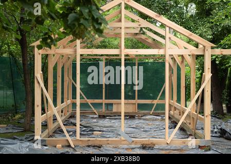 Costruzione di una grande serra in legno in giardino. Serra domestica in legno per la coltivazione di verdure o fiori Foto Stock