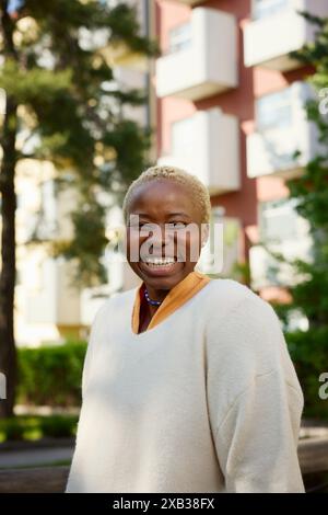 Giovane donna allegra in piedi contro l'edificio Foto Stock