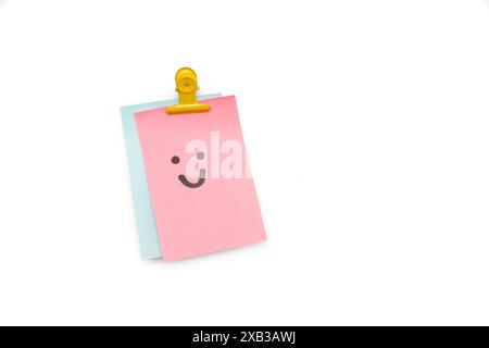 Nota di carta adesiva rosa con il disegno di un volto sorridente su uno sfondo bianco con spazio di copia Foto Stock