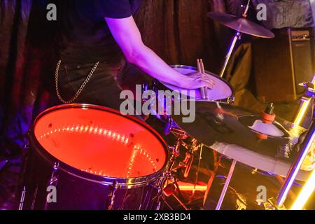 Batterista che si esibisce appassionatamente in un concerto rock con kit di batteria e piatti. Energia vibrante e creatività catturate nell'hobby musicale su sfondo nero Foto Stock