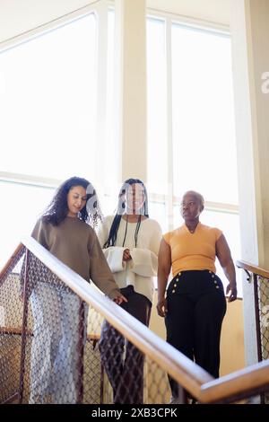 Vista ad angolo basso delle giovani amiche che si spostano giù sulle scale Foto Stock