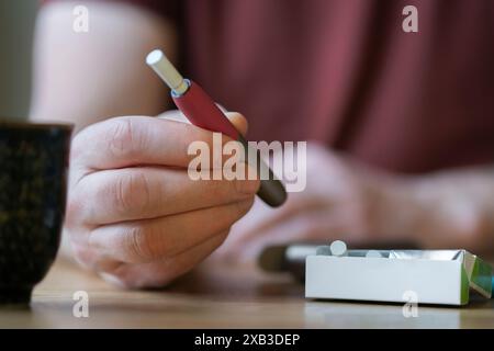 Persona che detiene sigarette elettroniche e un pacchetto di sigarette Foto Stock