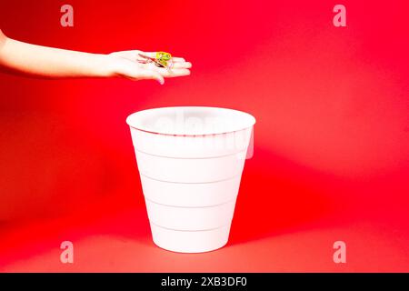 Una mano sta per lanciare un mucchio di chiavi nel cestino. Concetto di variazione dei prezzi immobiliari Foto Stock