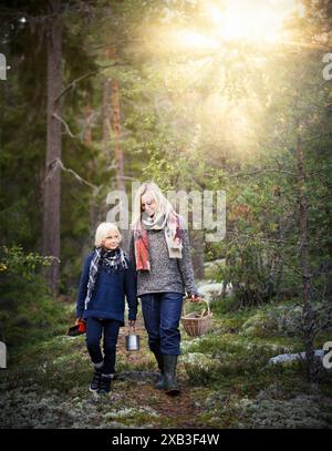 Madre e figlio sorridenti che camminano nella foresta Foto Stock