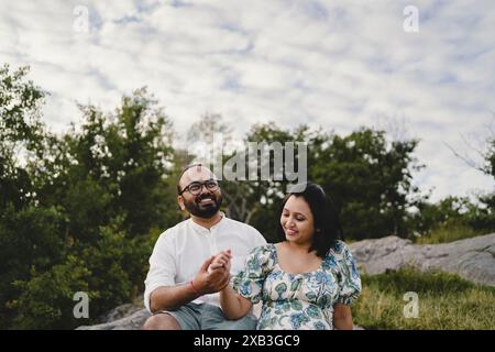 Coppia felice che si tiene per mano e si siede nel parco Foto Stock