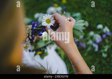 Immagine ritagliata di una donna che tiene un fiore bianco nel cortile posteriore Foto Stock