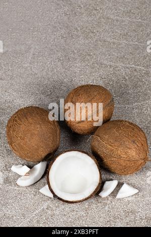 Noci di cocco intere e mezza noce di cocco su sfondo blu e grigio primo piano Foto Stock