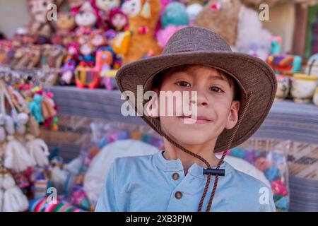 Ritratto del turista latino con cappello che guarda felicemente alla macchina fotografica, in vacanza ad una fiera dell'artigianato a Humahuaca, Argentina. Foto Stock