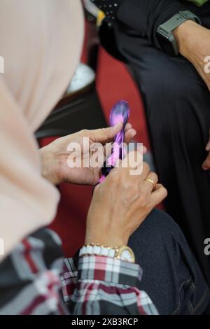 Una donna che indossa un hijab si sta concentrando sulla formazione di calze con il filo usando le mani ed è molto attenta Foto Stock