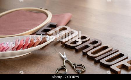 Lettere in legno con ricami e forbici su fondo in legno Foto Stock