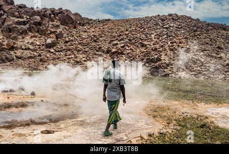 La guida turistica locale, vestita in modo tradizionale, mostra calde sorgenti vulcaniche naturali geotermiche con una piscina fumante e piccoli laghi colorati, geyser e insenature Foto Stock