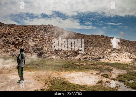 La guida turistica locale, vestita in modo tradizionale, mostra calde sorgenti vulcaniche naturali geotermiche con una piscina fumante e piccoli laghi colorati, geyser e insenature Foto Stock