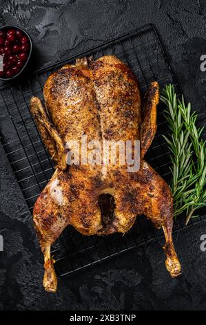 Arrosto d'anatra intera, ricetta natalizia. Sfondo nero. Vista dall'alto. Foto Stock