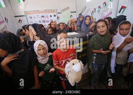 I bambini palestinesi sfollati si riuniscono intorno a un cubo improvvisato che rappresenta la Santa Kaaba i bambini palestinesi sfollati si riuniscono intorno a un cubo improvvisato che rappresenta la Santa Kaaba, in tenda all'interno di un campo per accogliere gli sfollati nell'ospedale dei Martiri di al-Aqsa, il 10 giugno 2024, come parte della formazione dei bambini come eseguire il pellegrinaggio Hajj che è uno dei cinque pilastri dell'Islam. Foto di Omar Ashtawy apaimages Dair EL-Balah Striscia di Gaza territorio palestinese 100624 Dair El-Balah OSH 2 0021 Copyright: XapaimagesxOmarxAshtawyxxapaimagesx Foto Stock