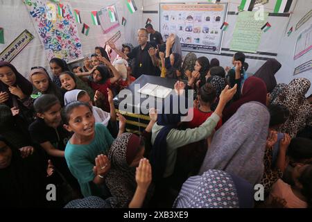 I bambini palestinesi sfollati si riuniscono intorno a un cubo improvvisato che rappresenta la Santa Kaaba i bambini palestinesi sfollati si riuniscono intorno a un cubo improvvisato che rappresenta la Santa Kaaba, in tenda all'interno di un campo per accogliere gli sfollati nell'ospedale dei Martiri di al-Aqsa, il 10 giugno 2024, come parte della formazione dei bambini come eseguire il pellegrinaggio Hajj che è uno dei cinque pilastri dell'Islam. Foto di Omar Ashtawy apaimages Dair EL-Balah Striscia di Gaza territorio palestinese 100624 Dair El-Balah OSH 2 0026 Copyright: XapaimagesxOmarxAshtawyxxapaimagesx Foto Stock