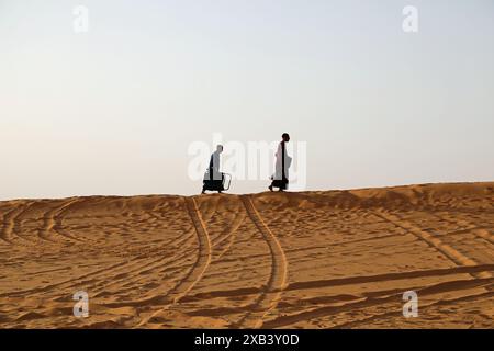 I turisti scalano le dune di sabbia a Taghit, nell'Algeria occidentale, per ammirare il tramonto Foto Stock