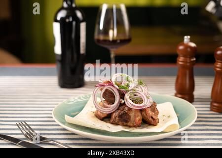 Pezzi di carne grigliata su un piatto bianco su sfondo scuro con bicchiere di vino. Griglia shish kebab. Foto Stock