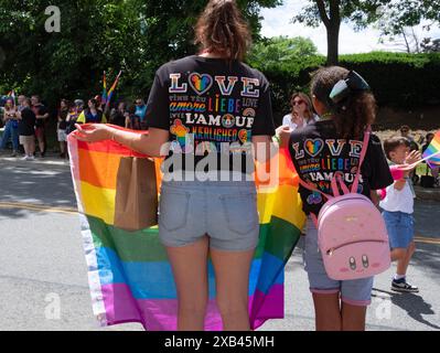 Vista posteriore di una madre e di una figlia che indossano una maglietta abbinata alla parola amore in diverse lingue. Sulla parata del 2024 Poughkeepsie Pride. Foto Stock