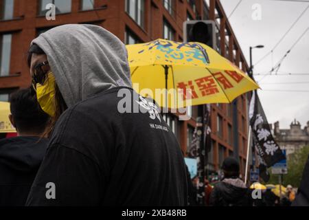 Un manifestante la cui camicia riporta la scritta "HK dark age” è stato visto guardare indietro mentre decine di manifestanti che portavano bandiere con la scritta "liberate Hong Kong, Revolution of Our Times” e ombrelli gialli che erano stati usati selvaggiamente dal movimento all'epoca, sono stati visti marciare a Manchester. Il popolo di Hong Kong ha tenuto una marcia di protesta nel centro di Manchester per commemorare il movimento democratico di Hong Kong cinque anni fa, una delle più grandi manifestazioni nella storia di Hong Kong, che in seguito ha portato alla repressione della polizia e a molti arresti, con conseguenti decine di migliaia di cittadini che lasciano la città Foto Stock