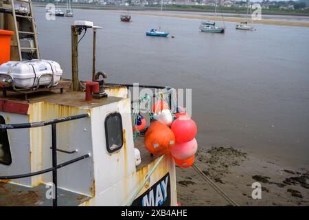 Barca da pesca attraccata in un tranquillo porto di Conwy Wales con boe colorate e barche a vela in lontananza Foto Stock