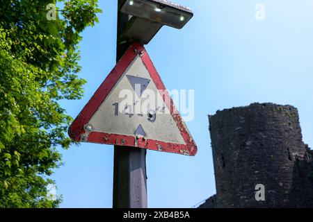 Conwy Wales Regno Unito 06-01-2024. Vecchio cartello triangolare di limitazione dell'altezza accanto alla torre di pietra sotto il cielo azzurro Foto Stock